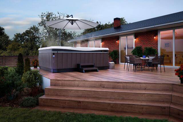 Hot tub with wooden privacy wall next to a brick house