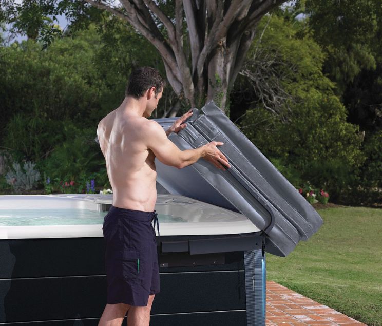 Man opening hot tub - Oregon Hot Tub explains why buying a spa cover during winter is best.