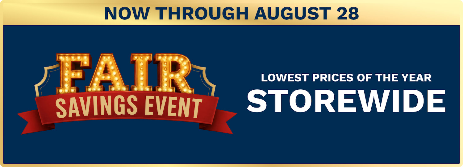 Promotional banner for a savings event: glowing 'FAIR' letters with a red ribbon reading 'SAVINGS EVENT' on a navy background, announcing 'NOW THROUGH AUGUST 28' and 'LOWEST PRICES OF THE YEAR STOREWIDE.'